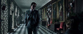 Movie still from “All the Money in the World” (2017), directed by Ridley Scott – A man in a suit standing in front of a painting; Medium shot, Low angle