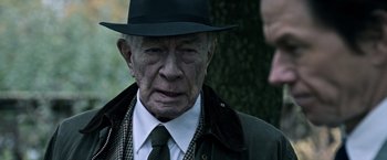 Movie still from “All the Money in the World” (2017), directed by Ridley Scott – An older man wearing a hat and a tie; Close Up shot, Over the shoulder angle