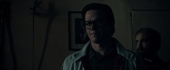 Movie still from “All the Money in the World” (2017), directed by Ridley Scott – A man with glasses is standing in a room; Close Up shot, Low angle