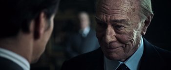 Movie still from “All the Money in the World” (2017), directed by Ridley Scott – An older man in a suit and tie looking down; Close Up shot, Over the shoulder angle