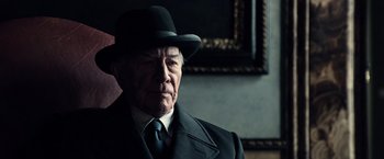 Movie still from “All the Money in the World” (2017), directed by Ridley Scott – An older man in a suit and hat; Close Up shot, Low angle