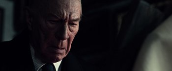 Movie still from “All the Money in the World” (2017), directed by Ridley Scott – An older man wearing a suit and tie looking down; Close Up shot, Low angle
