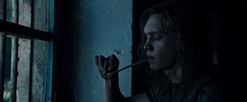 Movie still from “All the Money in the World” (2017), directed by Ridley Scott – A person with long hair is holding a cigarette in his mouth; Close Up shot, Low angle