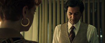 Movie still from “All the Money in the World” (2017), directed by Ridley Scott – A man wearing a vest and a striped tie; Medium shot, Over the shoulder angle