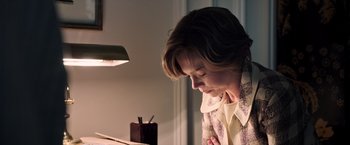 Movie still from “All the Money in the World” (2017), directed by Ridley Scott – A woman sitting in front of a desk looking down at papers; Medium shot, High angle