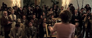 Movie still from “All the Money in the World” (2017), directed by Ridley Scott – A group of men and women in a room; Medium shot, High angle