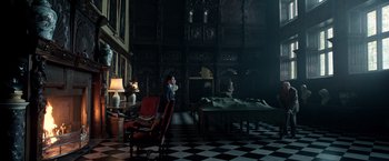 Movie still from “All the Money in the World” (2017), directed by Ridley Scott – A man sitting on a chair in a dark room; Extreme Wide shot, High angle