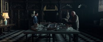 Movie still from “All the Money in the World” (2017), directed by Ridley Scott – A man standing in front of a table with a model of a building; Extreme Wide shot, High angle