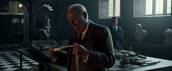 Movie still from “All the Money in the World” (2017), directed by Ridley Scott – An older man in a suit and tie looking at papers; Medium shot, Low angle