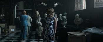 Movie still from “All the Money in the World” (2017), directed by Ridley Scott – A woman standing in front of a room filled with statues; Medium shot, Over the shoulder angle