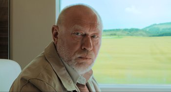 Movie still from “Gemini Man” (2019), directed by Ang Lee – An old man with a beard and a white beard looking out of a window; Close Up shot, Low angle
