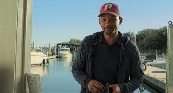 Movie still from “Gemini Man” (2019), directed by Ang Lee – A man wearing a baseball hat standing in front of a body of water; Medium shot, Over the shoulder angle