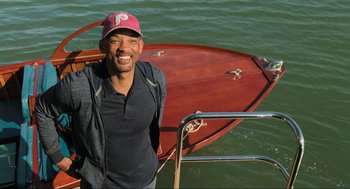 Movie still from “Gemini Man” (2019), directed by Ang Lee – A man standing in front of a boat in the water; Medium shot, Overhead angle