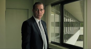 Movie still from “Gemini Man” (2019), directed by Ang Lee – A man in a suit and tie standing in front of a window; Medium shot, Low angle