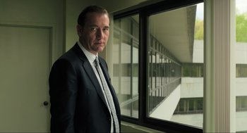 Movie still from “Gemini Man” (2019), directed by Ang Lee – A man in a suit and tie standing in front of a window; Medium shot, Low angle