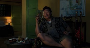 Movie still from “Gemini Man” (2019), directed by Ang Lee – A man sitting in a chair holding a book; Medium shot, High angle
