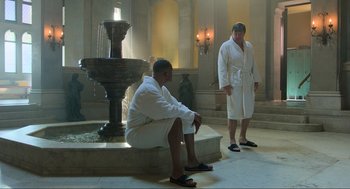 Movie still from “Gemini Man” (2019), directed by Ang Lee – Two men in white robes are sitting in front of a fountain; Wide shot, Low angle