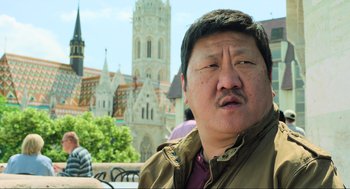 Movie still from “Gemini Man” (2019), directed by Ang Lee – A man in a brown jacket is standing in front of a church; Close Up shot, Low angle