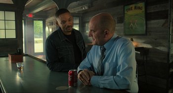 Movie still from “Gemini Man” (2019), directed by Ang Lee – Two men sitting at a table with a drink in front of them; Medium shot, Over the shoulder angle