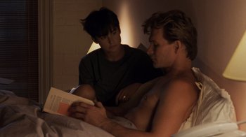 Movie still from “Ghost” (1990), directed by Jerry Zucker – A man reading a book in bed with another man; Medium shot, High angle