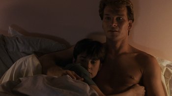 Movie still from “Ghost” (1990), directed by Jerry Zucker – A man and a boy in a bed with a blanket; Medium shot, High angle