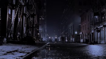 Movie still from “Ghost” (1990), directed by Jerry Zucker – A city street at night lit by street lights; Extreme Wide shot, High angle