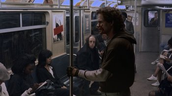 Movie still from “Ghost” (1990), directed by Jerry Zucker – A man with blood all over his face riding on a subway train; Wide shot, Over the shoulder angle