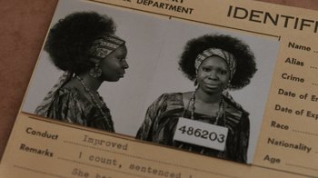 Movie still from “Ghost” (1990), directed by Jerry Zucker – A black and white photo of a woman in a police department photo; Close Up shot, High angle