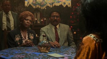 Movie still from “Ghost” (1990), directed by Jerry Zucker – A man and woman sitting at a table with a bottle; Medium shot, Over the shoulder angle