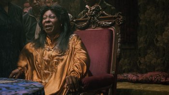 Movie still from “Ghost” (1990), directed by Jerry Zucker – An older woman sitting on a chair in a living room; Medium shot, Over the shoulder angle