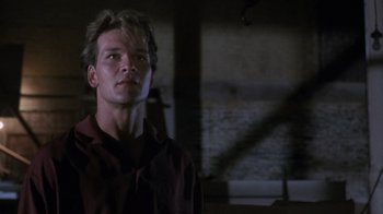 Movie still from “Ghost” (1990), directed by Jerry Zucker – A man in a red shirt is standing in a dark room; Close Up shot, Low angle