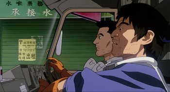 Movie still from “Ghost in the Shell” (1995), directed by Mamoru Oshii – A couple of men sitting in the drivers seat of a car; Close Up shot, Low angle