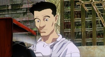Movie still from “Ghost in the Shell” (1995), directed by Mamoru Oshii – A man with a surprised look on his face in front of a building; Close Up shot, Low angle