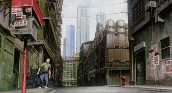 Movie still from “Ghost in the Shell” (1995), directed by Mamoru Oshii – A man standing on a street near a tall building; Extreme Wide shot, Low angle
