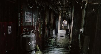 Movie still from “Ghost in the Shell” (1995), directed by Mamoru Oshii – A woman walking down a hallway in an old building; Wide shot, High angle