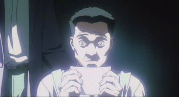 Movie still from “Ghost in the Shell” (1995), directed by Mamoru Oshii – A man holding a piece of paper in front of his face; Close Up shot, Low angle