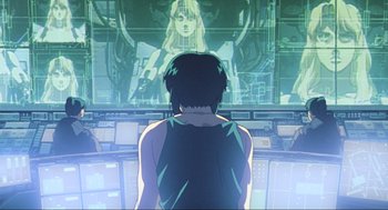 Movie still from “Ghost in the Shell” (1995), directed by Mamoru Oshii – A man standing in front of a large screen television; Medium shot, Low angle