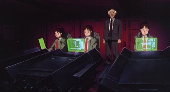 Movie still from “Ghost in the Shell” (1995), directed by Mamoru Oshii – A computer screen in front of a computer desk and a man in a suit; Wide shot, High angle