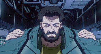 Movie still from “Ghost in the Shell” (1995), directed by Mamoru Oshii – A man with a beard is looking at the camera; Close Up shot, Low angle
