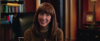 Movie still from “Ghostbusters” (2016), directed by Paul Feig – A woman with brown hair and bangs smiles for the camera; Close Up shot, Over the shoulder angle