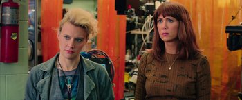Movie still from “Ghostbusters” (2016), directed by Paul Feig – Two women are standing next to each other in a room; Close Up shot, Over the shoulder angle