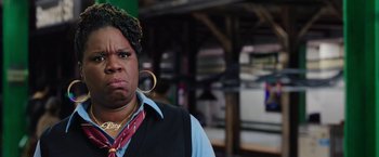 Movie still from “Ghostbusters” (2016), directed by Paul Feig – A woman with a large earring is standing in front of a building; Close Up shot, Over the shoulder angle