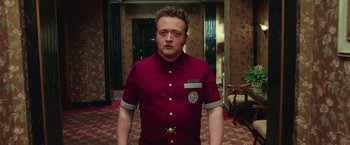 Movie still from “Ghostbusters” (2016), directed by Paul Feig – A man in a red shirt is standing in a room; Medium shot, Low angle