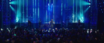 Movie still from “Ghostbusters” (2016), directed by Paul Feig – A man standing on a stage in front of an audience; Extreme Wide shot, High angle