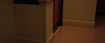 Movie still from “Ghostbusters” (2016), directed by Paul Feig – The corner of a room with a door and a floor; Medium shot, High angle