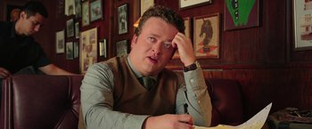 Movie still from “Ghostbusters” (2016), directed by Paul Feig – A man sitting at a table with a pen in his hand; Close Up shot, High angle