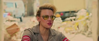 Movie still from “Ghostbusters” (2016), directed by Paul Feig – A woman with blonde hair wearing sunglasses and a brown jacket; Close Up shot, Over the shoulder angle