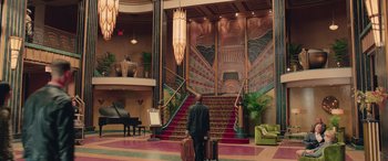 Movie still from “Ghostbusters” (2016), directed by Paul Feig – A man with luggage standing in front of a staircase; Extreme Wide shot, Low angle