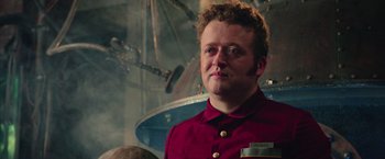Movie still from “Ghostbusters” (2016), directed by Paul Feig – A man in a red shirt is standing in front of a space ship; Close Up shot, Low angle