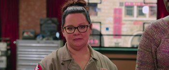 Movie still from “Ghostbusters” (2016), directed by Paul Feig – A woman wearing glasses and a brown shirt; Close Up shot, Over the shoulder angle